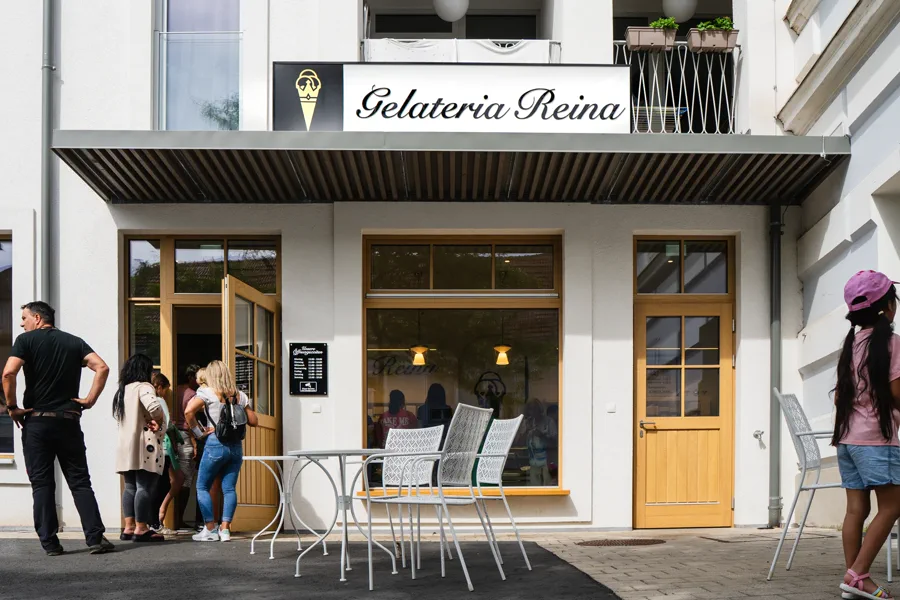Die Gelateria Reina von außen – weiße Fassade mit goldener Eistüte am Schild